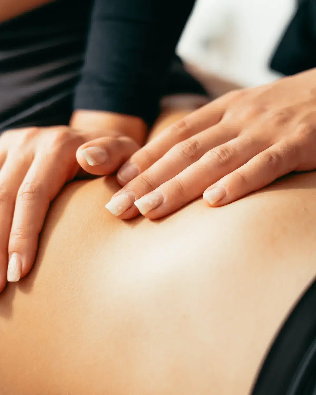 Practitioner's hands working along a patient's lower back